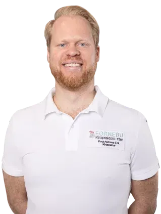 Smilende mann med rødt skjegg og blondt hår, iført en hvit poloskjorte med logo på skjorten.