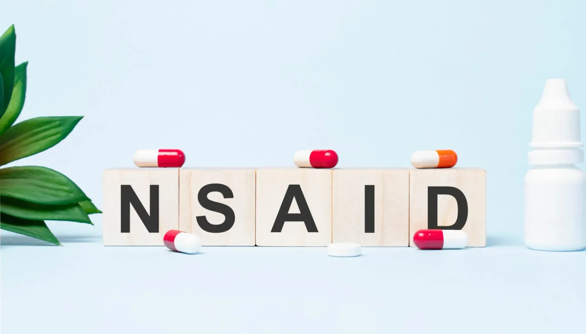 Treklosser som staver NSAID, piller, en liten plante og en hvit flaske på en lyseblå overflate.