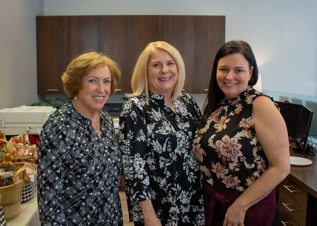 Three women are posing for a picture together in a kitchen.