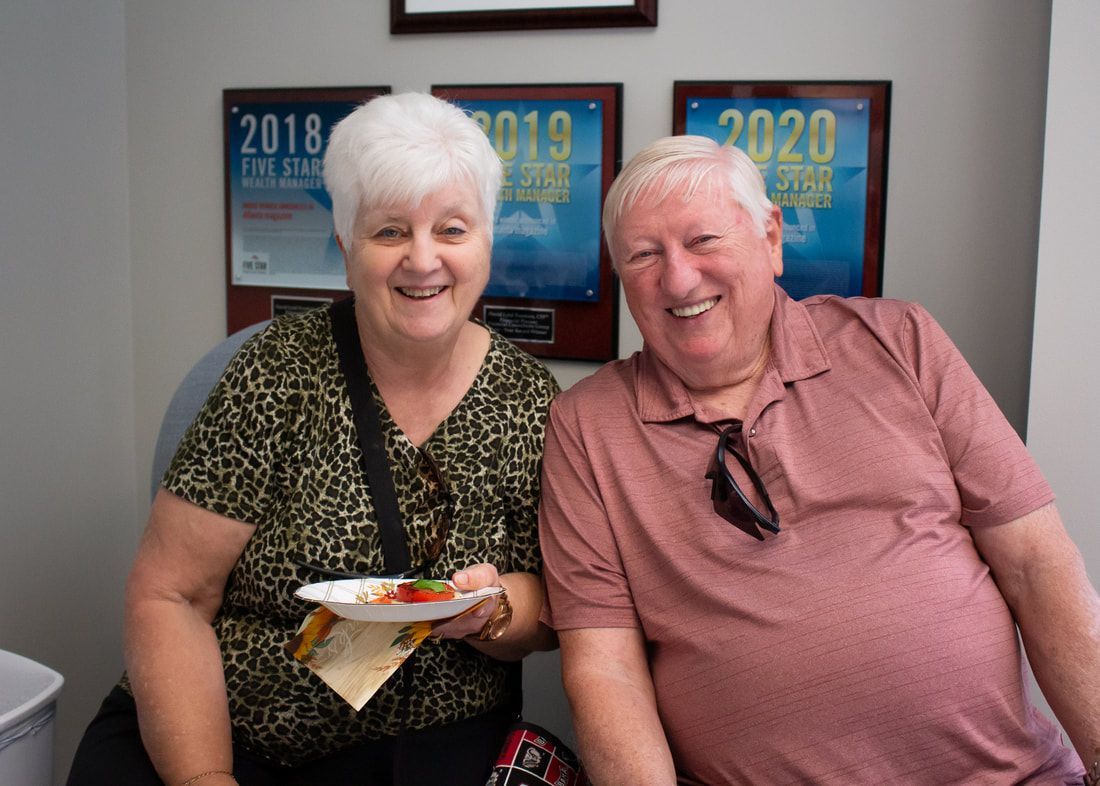 A man and a woman are posing for a picture while holding plates of food.