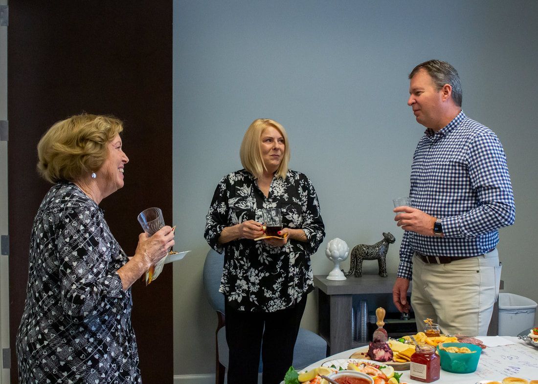 A group of people are standing around a table talking to each other.