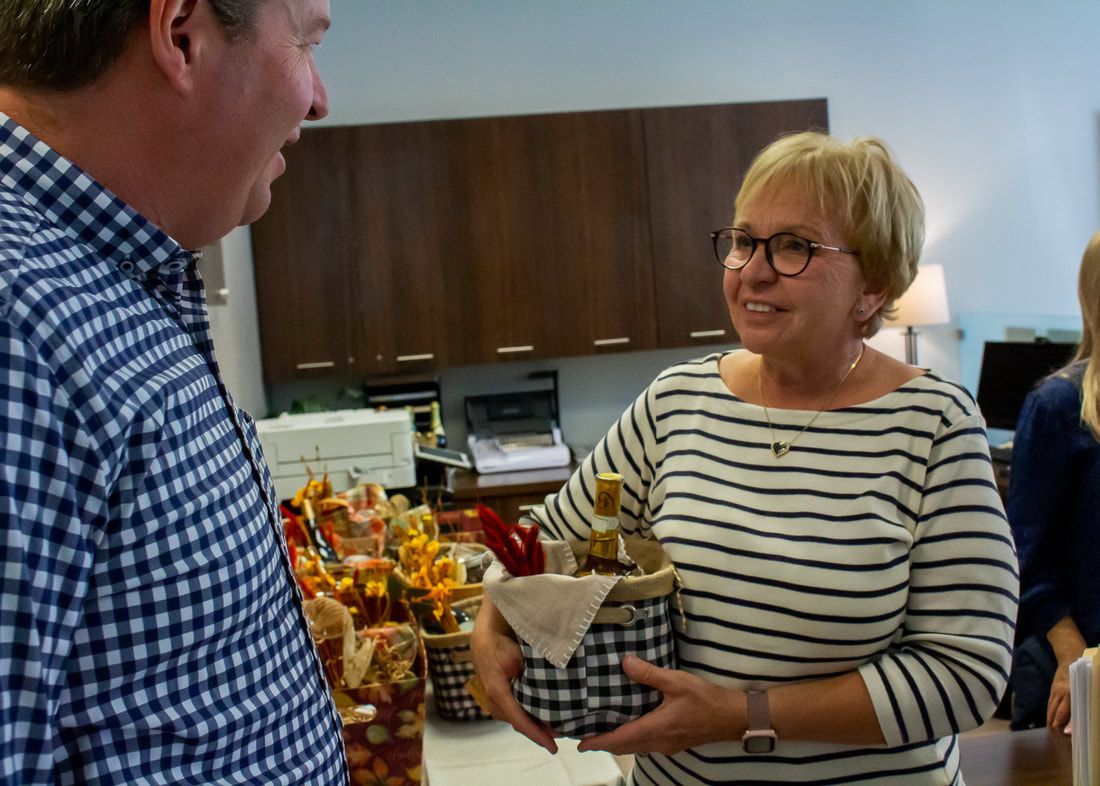 A woman in a striped shirt is holding a basket and talking to a man in a plaid shirt.
