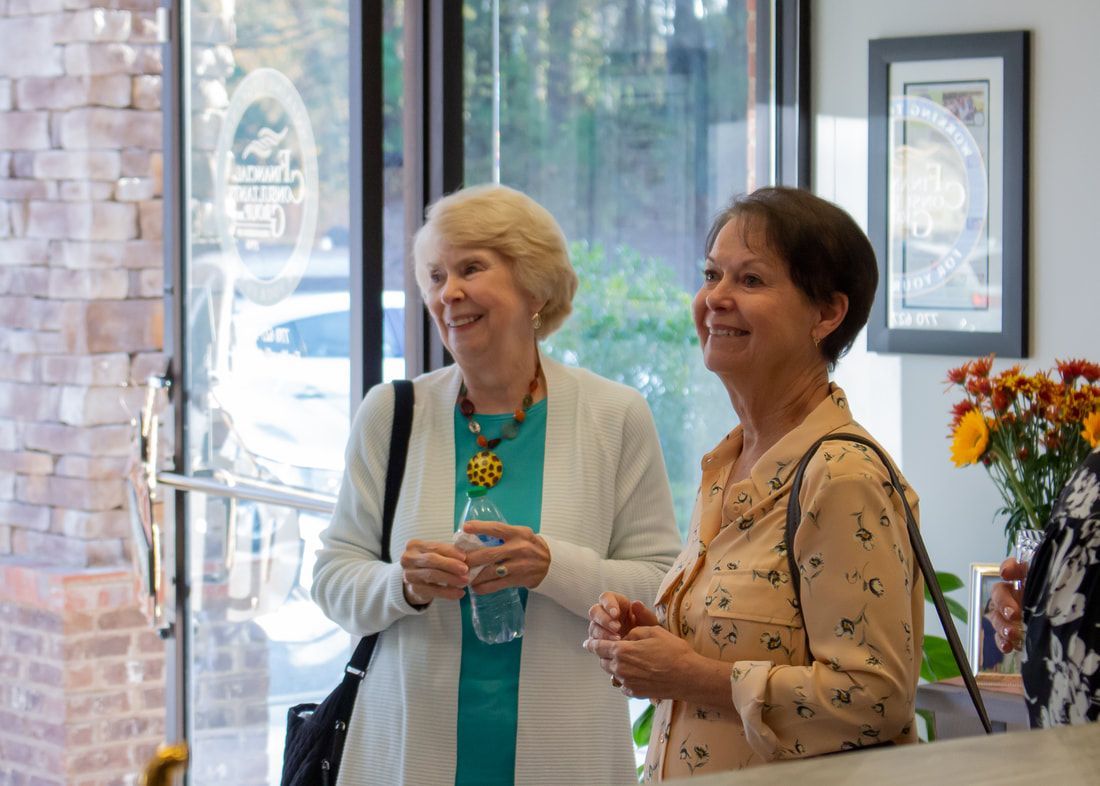 Two women are standing next to each other in a room and smiling.