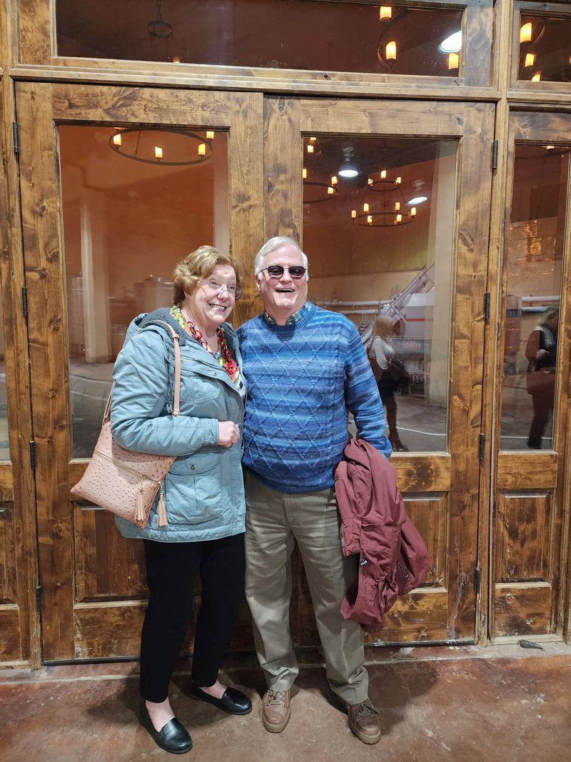 A man and a woman are posing for a picture in front of a wooden door.