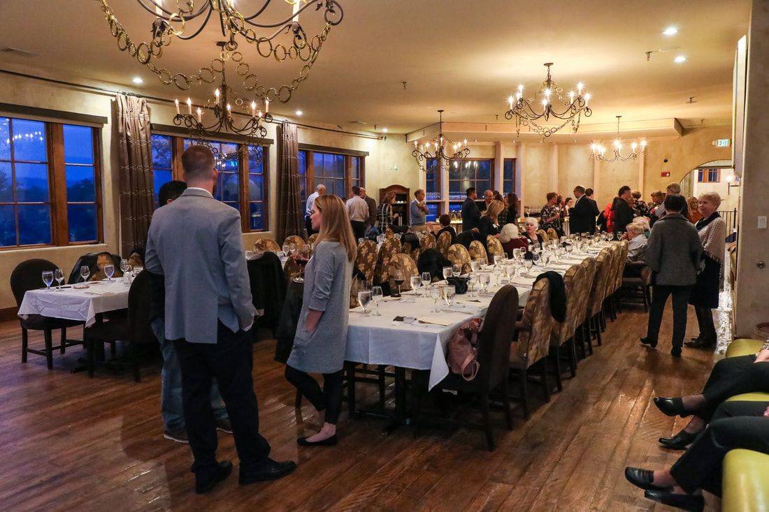 A group of people are standing around a long table in a restaurant.