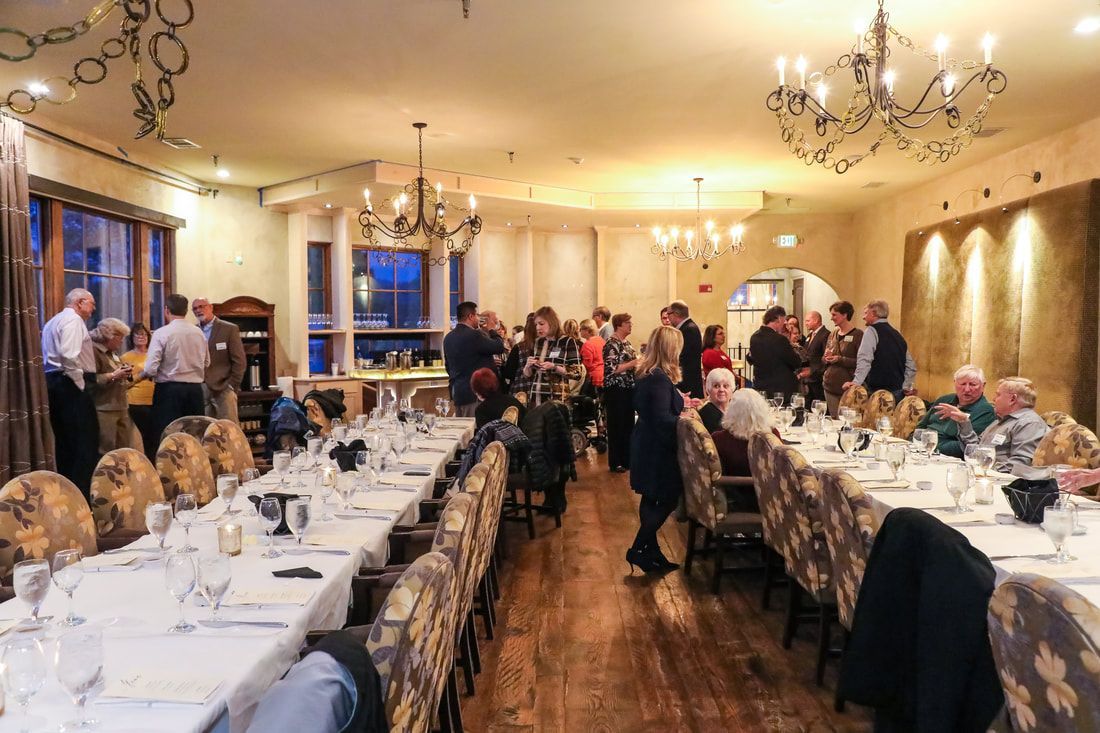 A group of people are sitting at long tables in a restaurant.