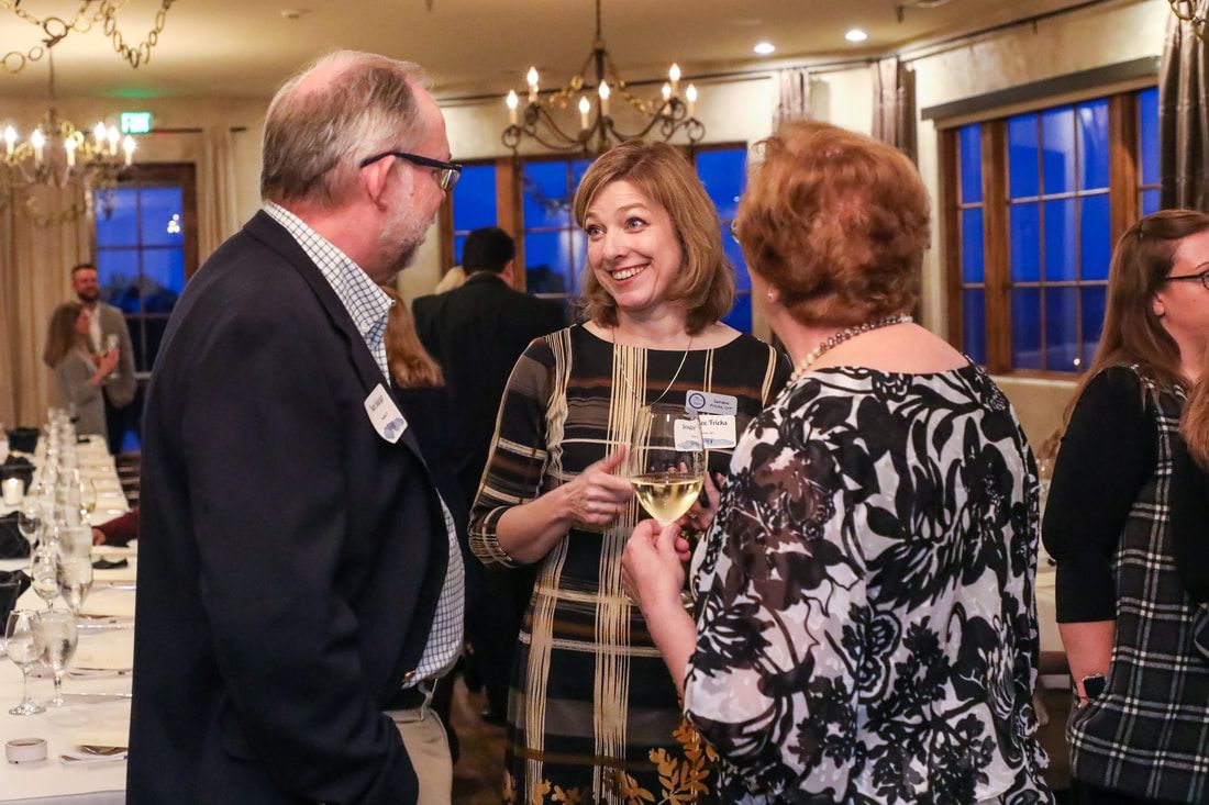 A group of people are standing around a table talking to each other.