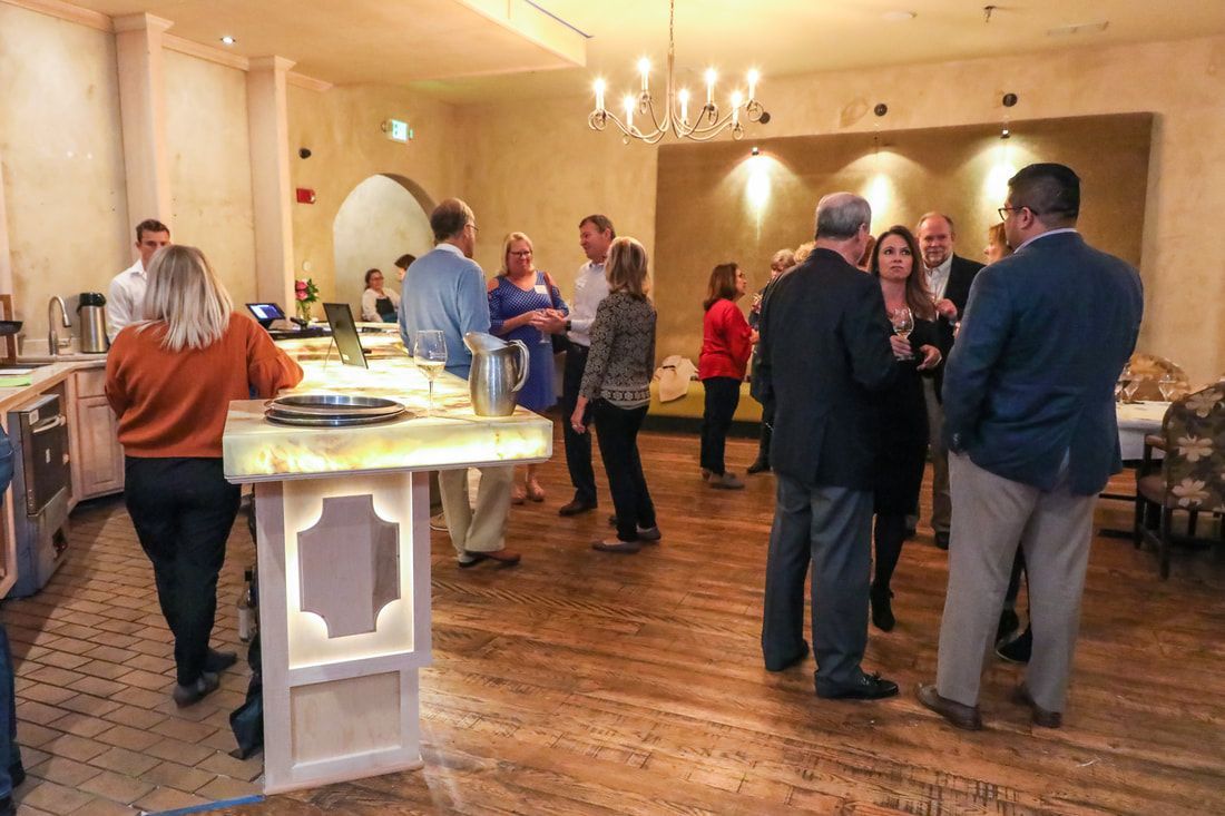 A group of people are standing in a room talking to each other.