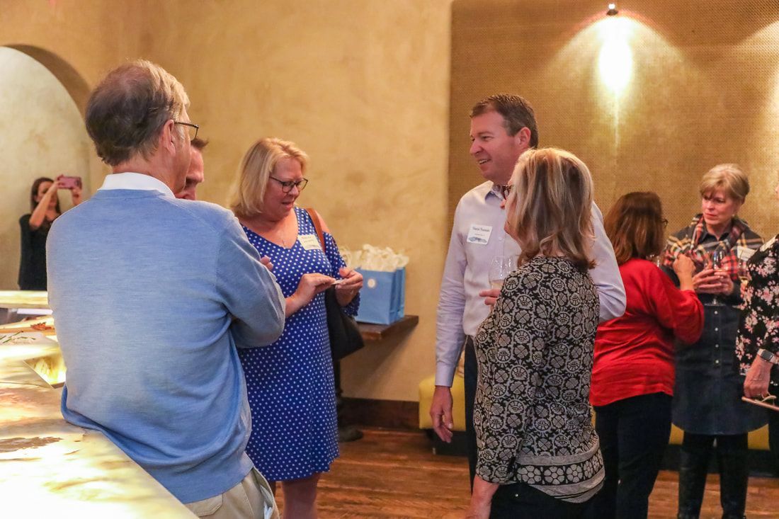 A group of people are standing in a room talking to each other