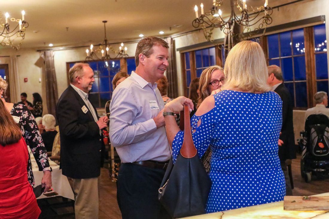 A group of people are standing in a room talking to each other.