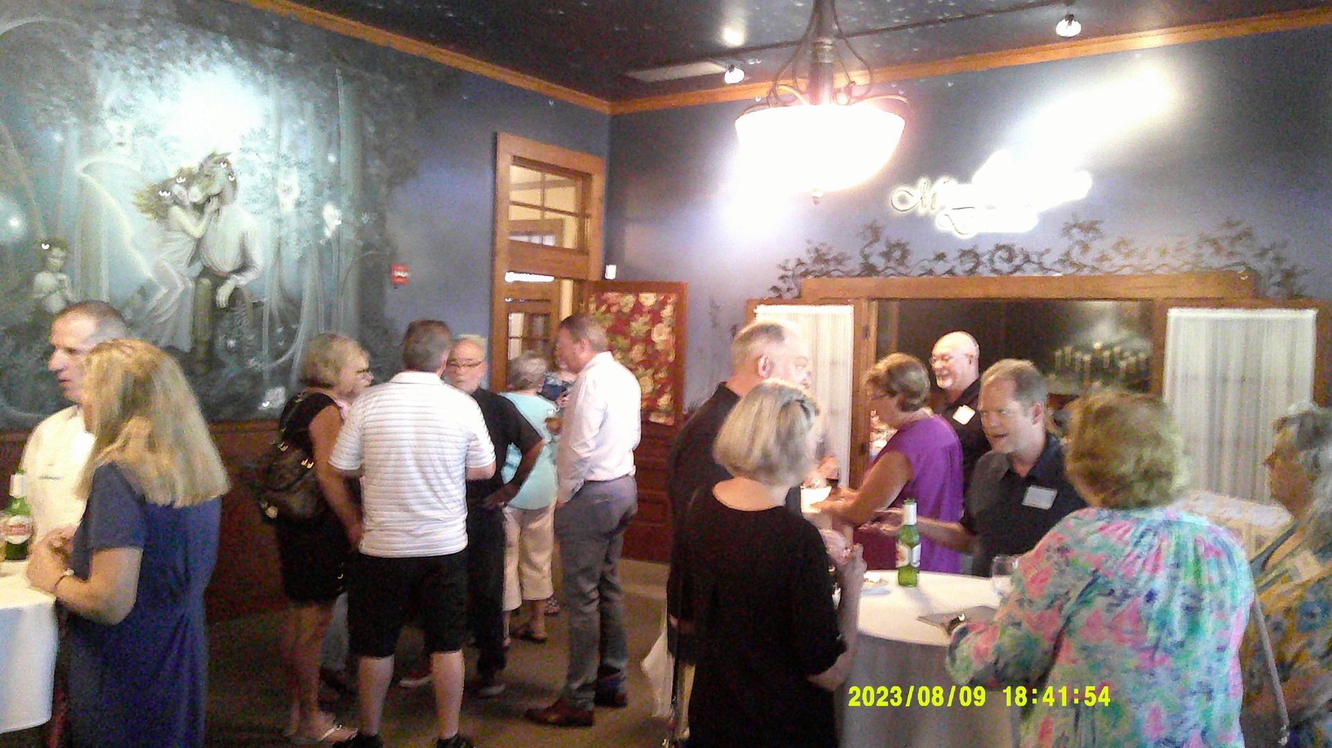 A group of people are standing in a room talking to each other.