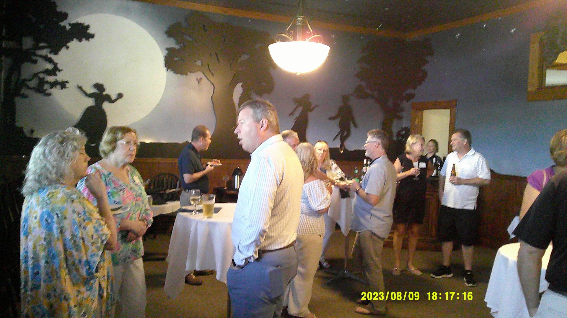 A group of people are standing in a room talking to each other.