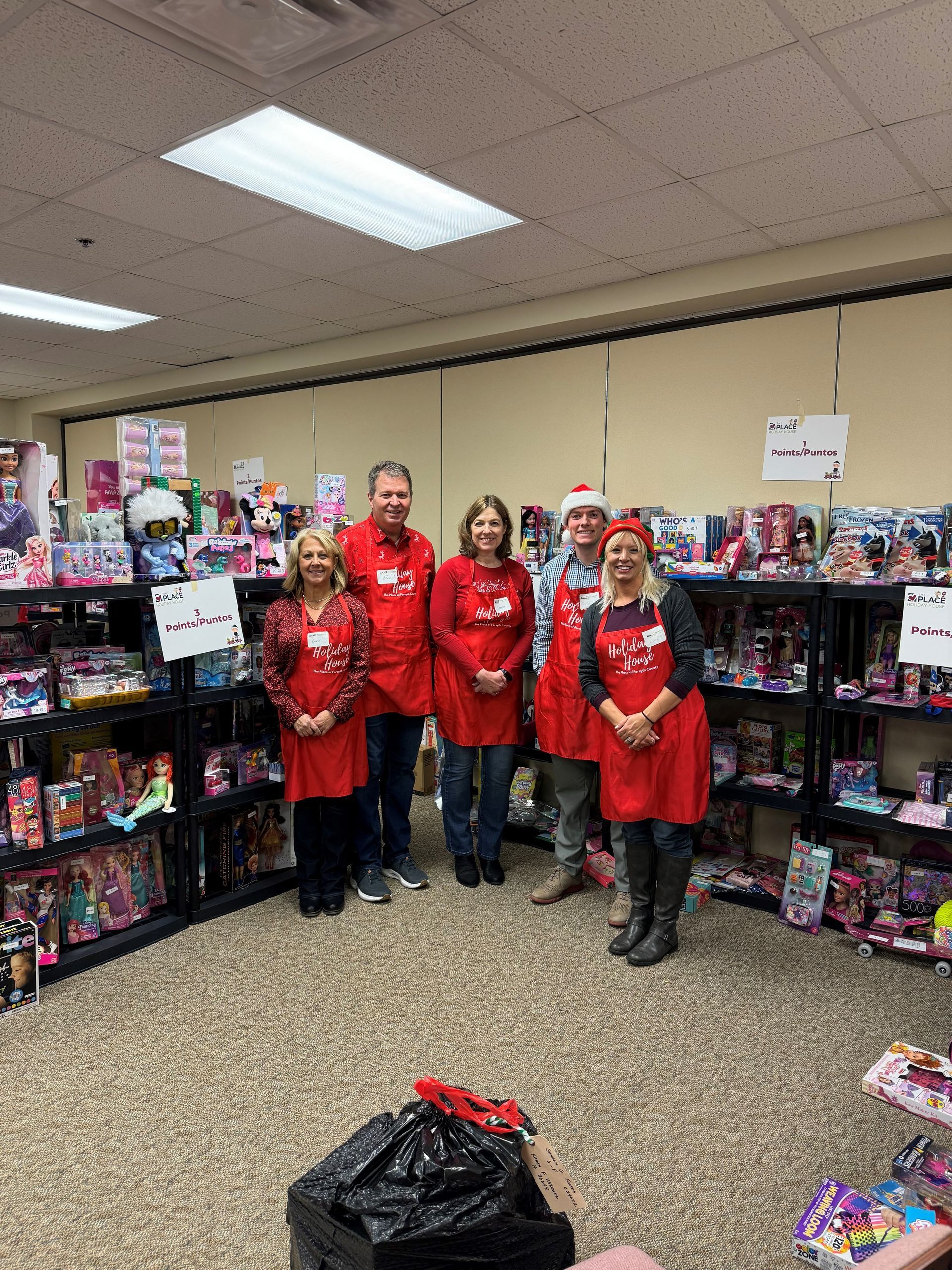 A group of people are standing in a room filled with lots of toys.
