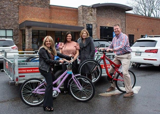 A group of people standing next to bicycles in front of a building.