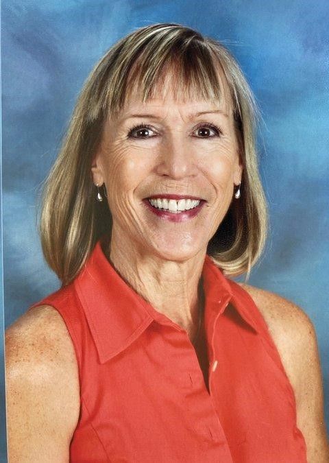 A woman in a red shirt is smiling for the camera.