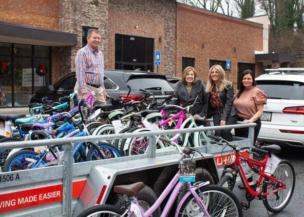 A group of people are standing next to a trailer full of bicycles.