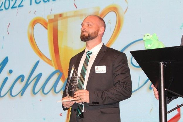 A man in a suit and tie is holding a trophy