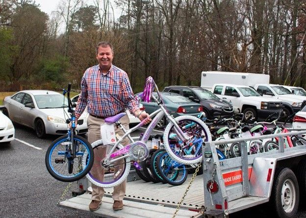 A man is holding a bicycle in front of a trailer full of bikes.