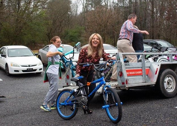 A woman is standing next to a blue bike in a parking lot