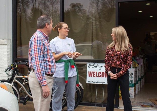 A group of people standing in front of a building with a welcome sign.
