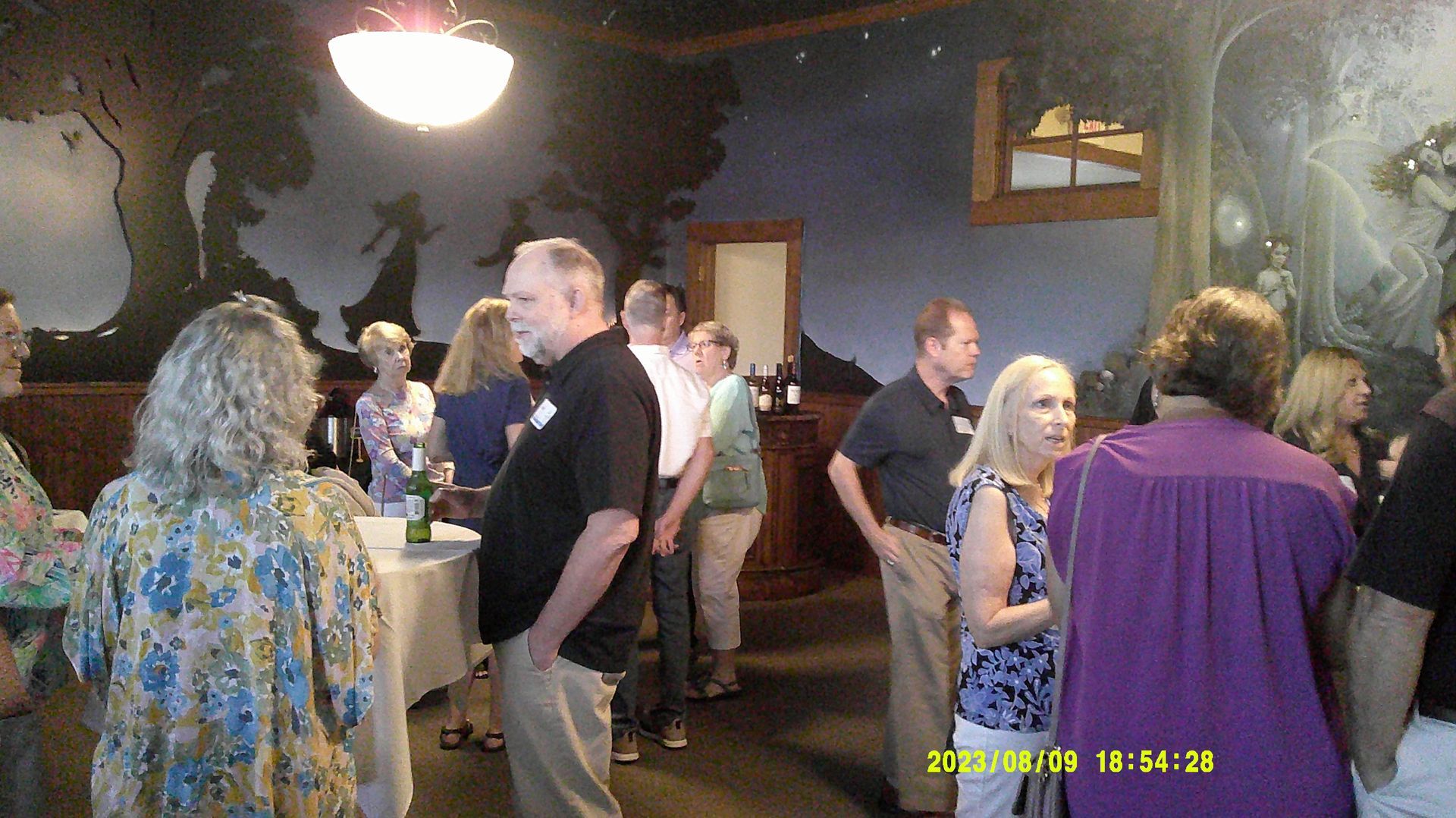 A group of people are standing in a room talking to each other.