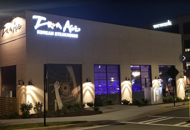A restaurant called iron age is lit up at night