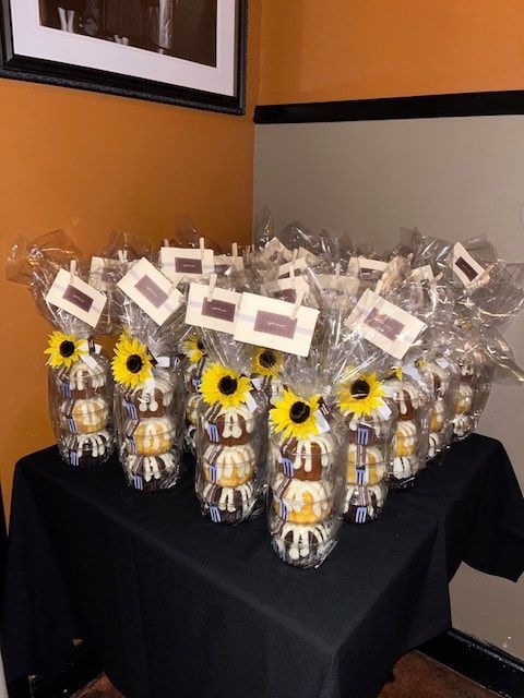 A table topped with a bunch of bags filled with cupcakes and sunflowers.