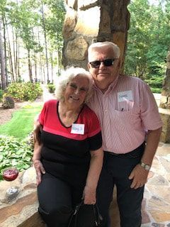 A man and a woman are posing for a picture on a porch.