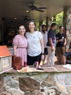 Two women are posing for a picture on a stone porch.
