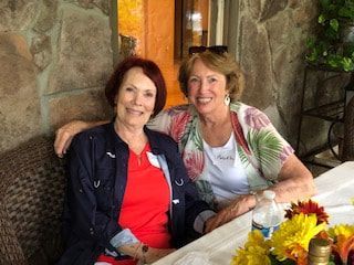 Two women are sitting next to each other at a table.