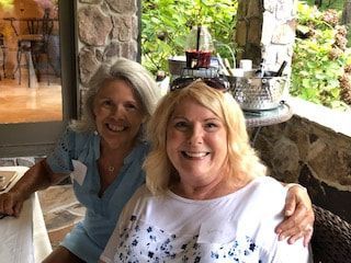 Two women are posing for a picture while sitting at a table.