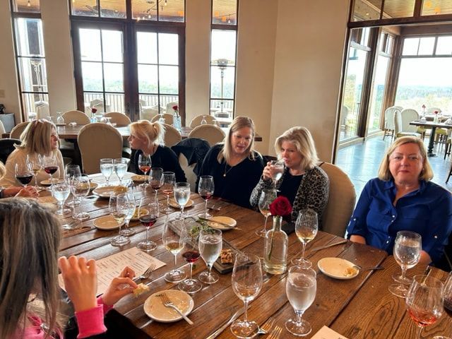 A group of women are sitting at a table with wine glasses.