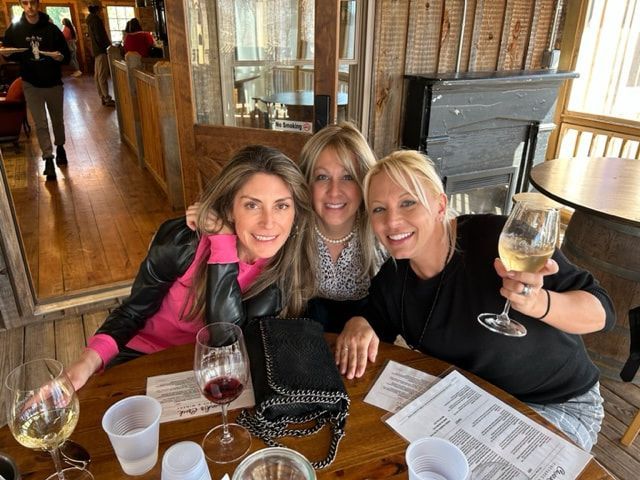 Three women are sitting at a table holding wine glasses.
