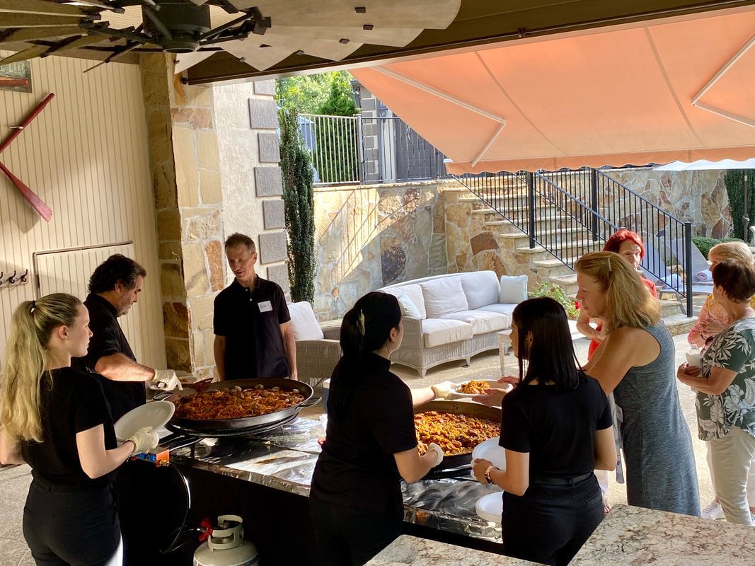 A group of people are standing around a table eating food.