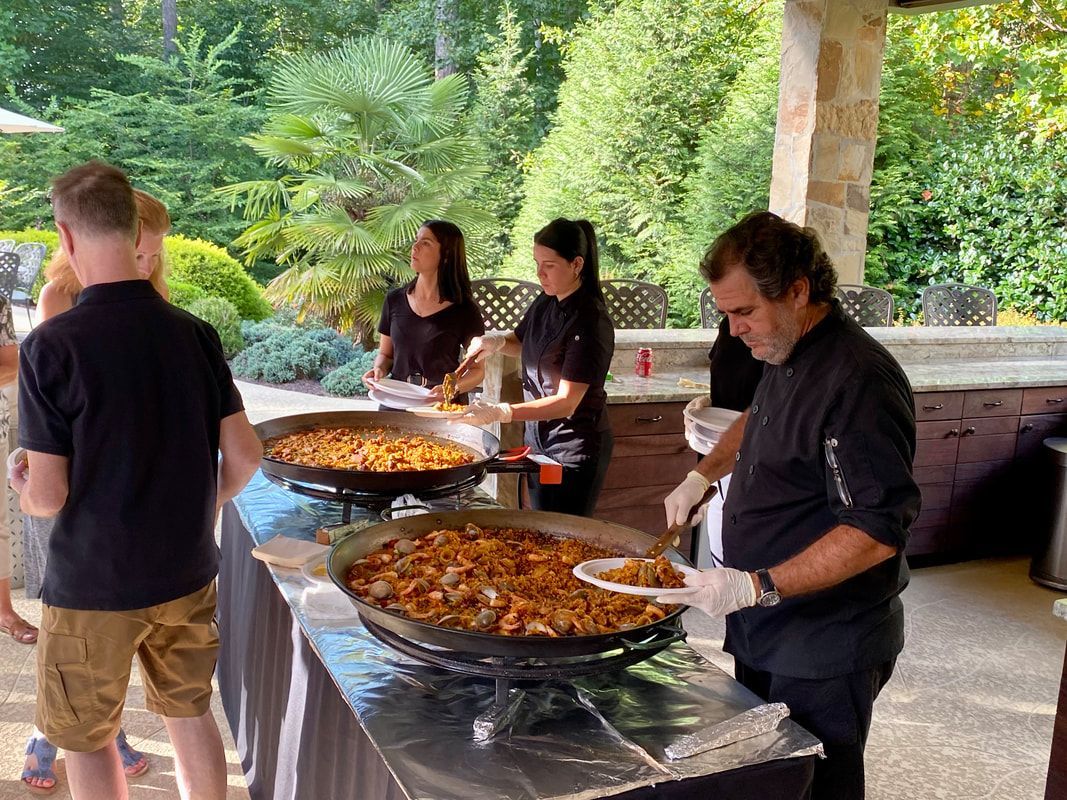 A group of people are standing around a table serving food.