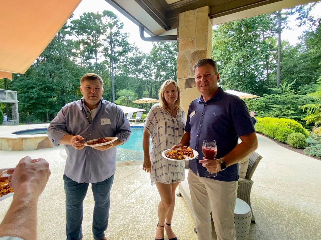 A group of people standing on a patio holding plates of food
