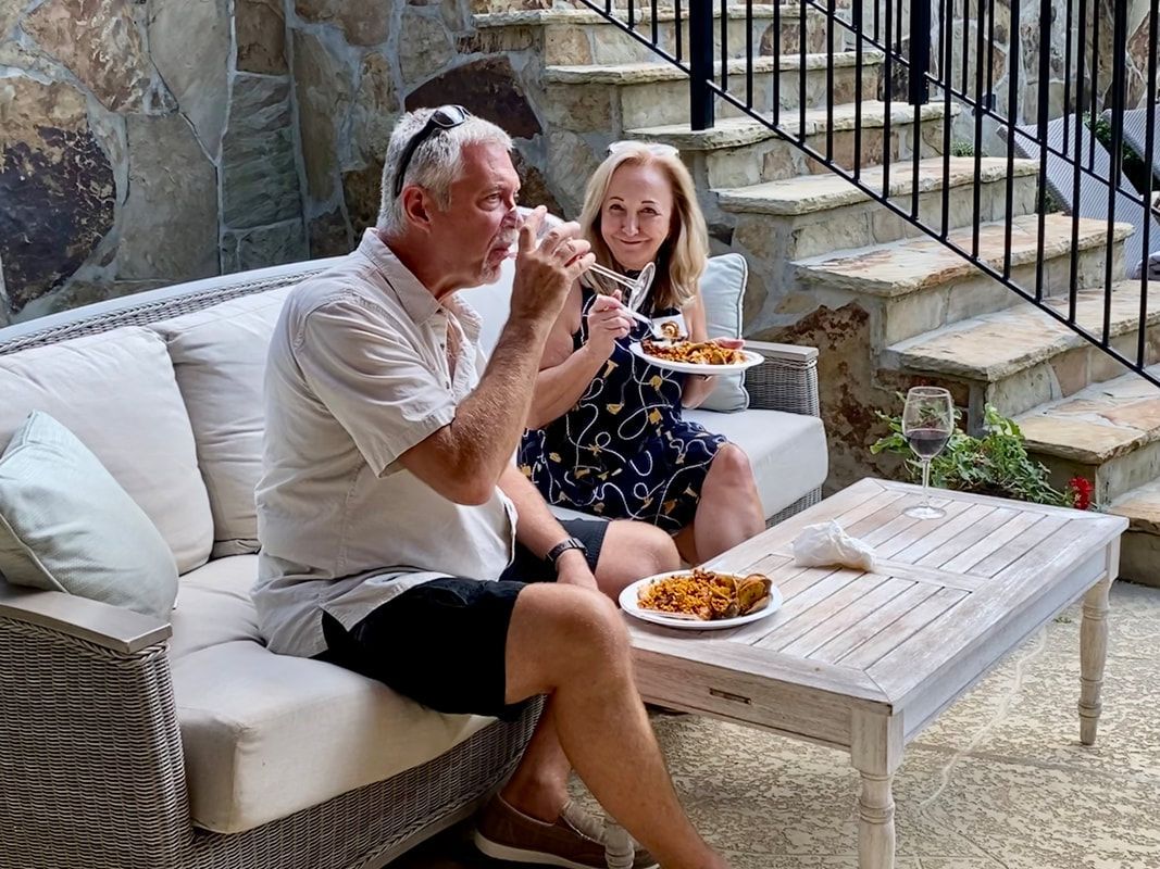 A man and a woman are sitting on a couch eating food.