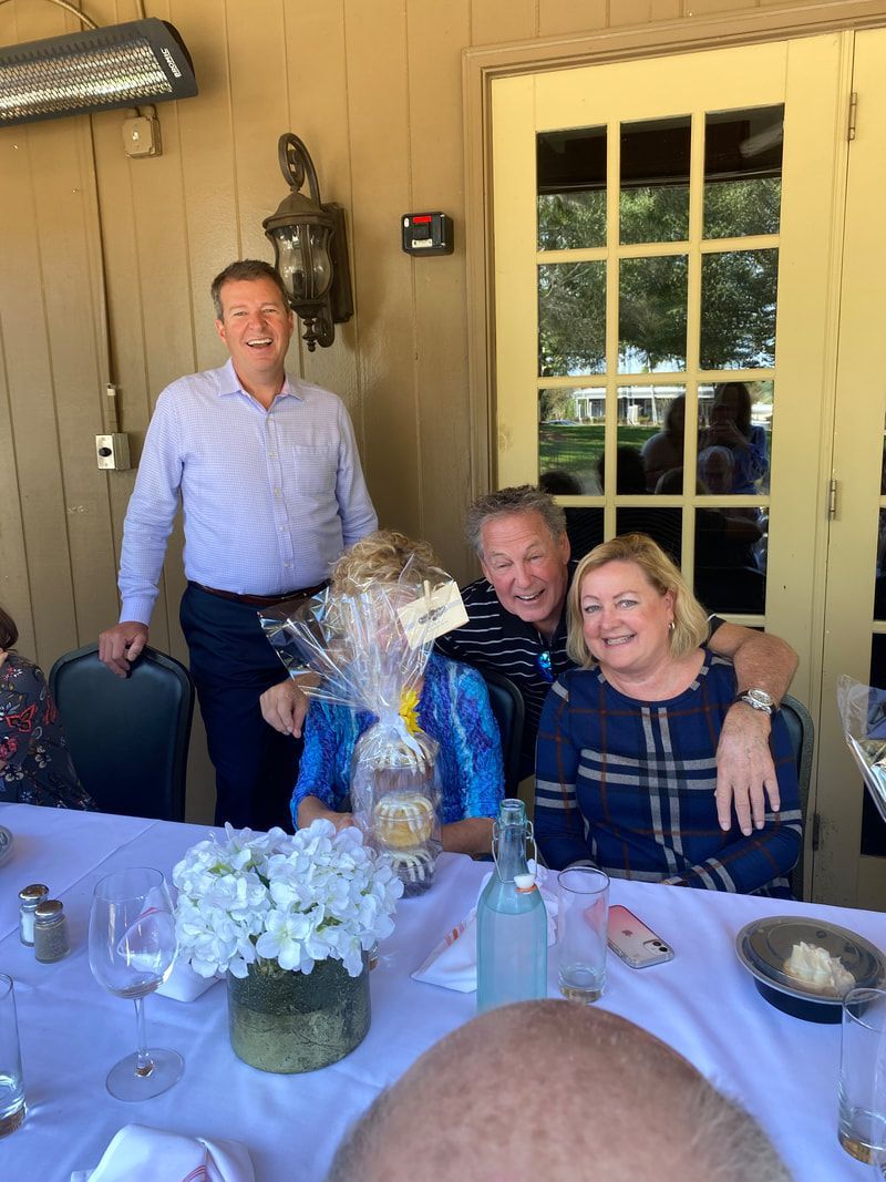 A group of people sitting at a table with a man standing behind them