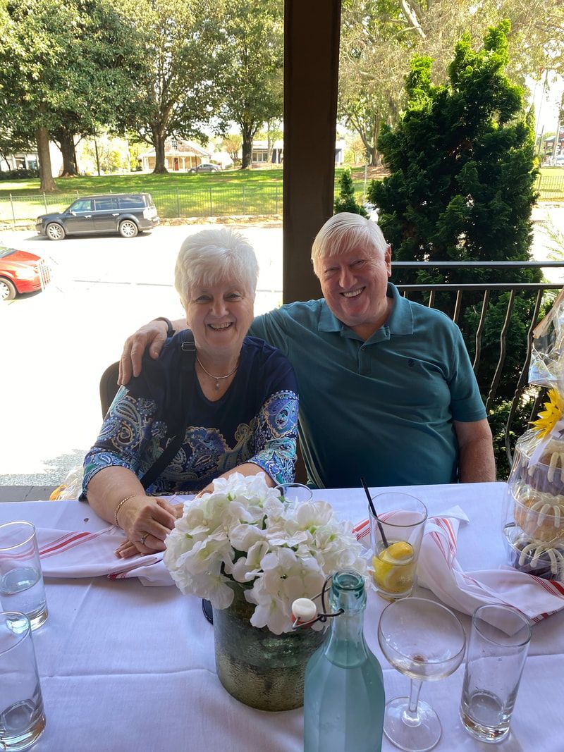 A man and a woman are sitting at a table with a vase of flowers.