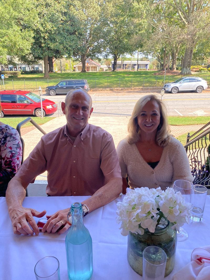 A man and a woman are sitting at a table with a vase of flowers.