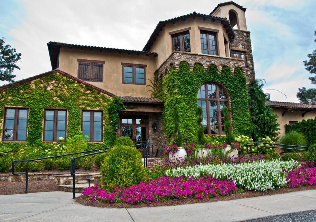 A large house with a lot of windows and flowers in front of it