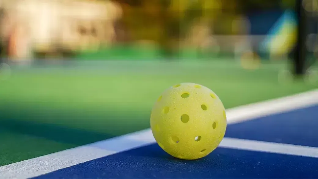 A yellow ball is sitting on a tennis court.