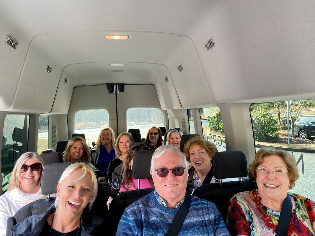 A group of people are sitting in the back of a van and smiling.