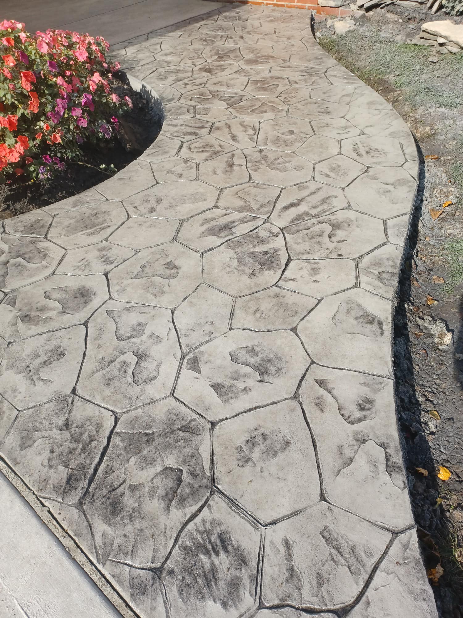 A concrete walkway with a flower bed in the middle of it.