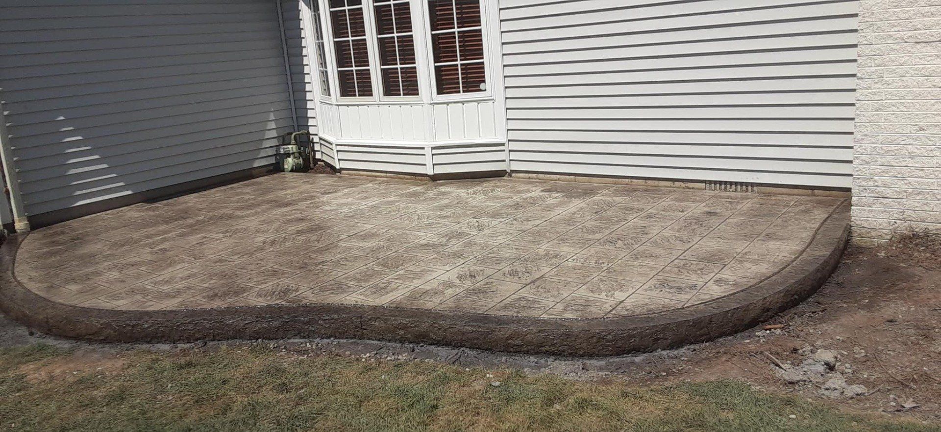 A concrete patio is being built in front of a house.