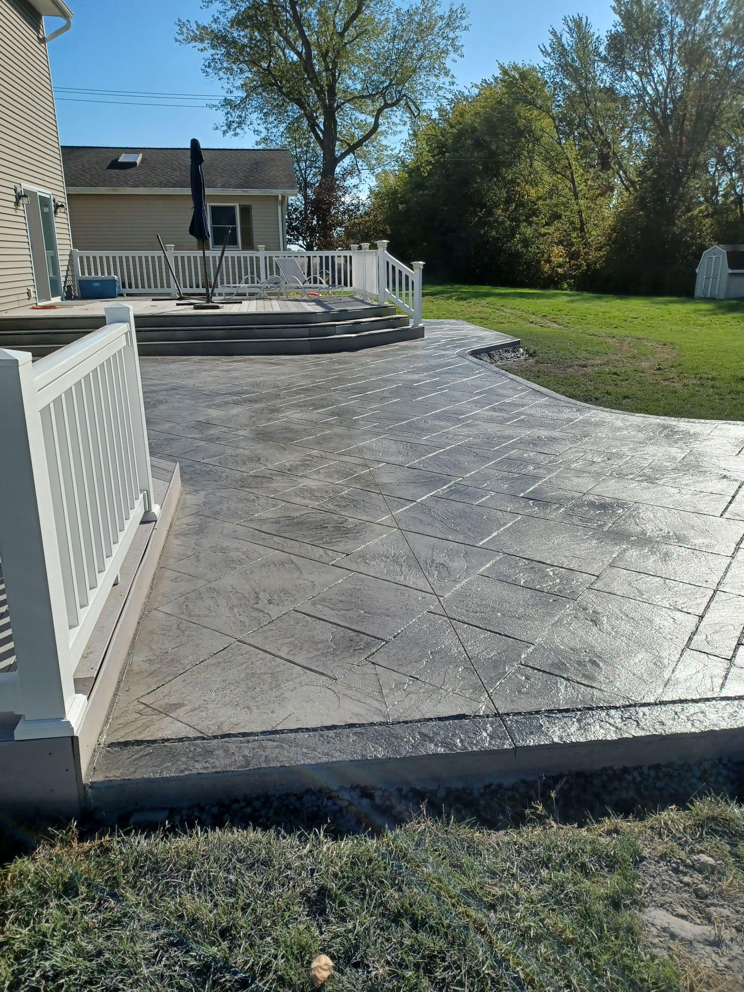 A patio with a deck and stairs in the backyard of a house.