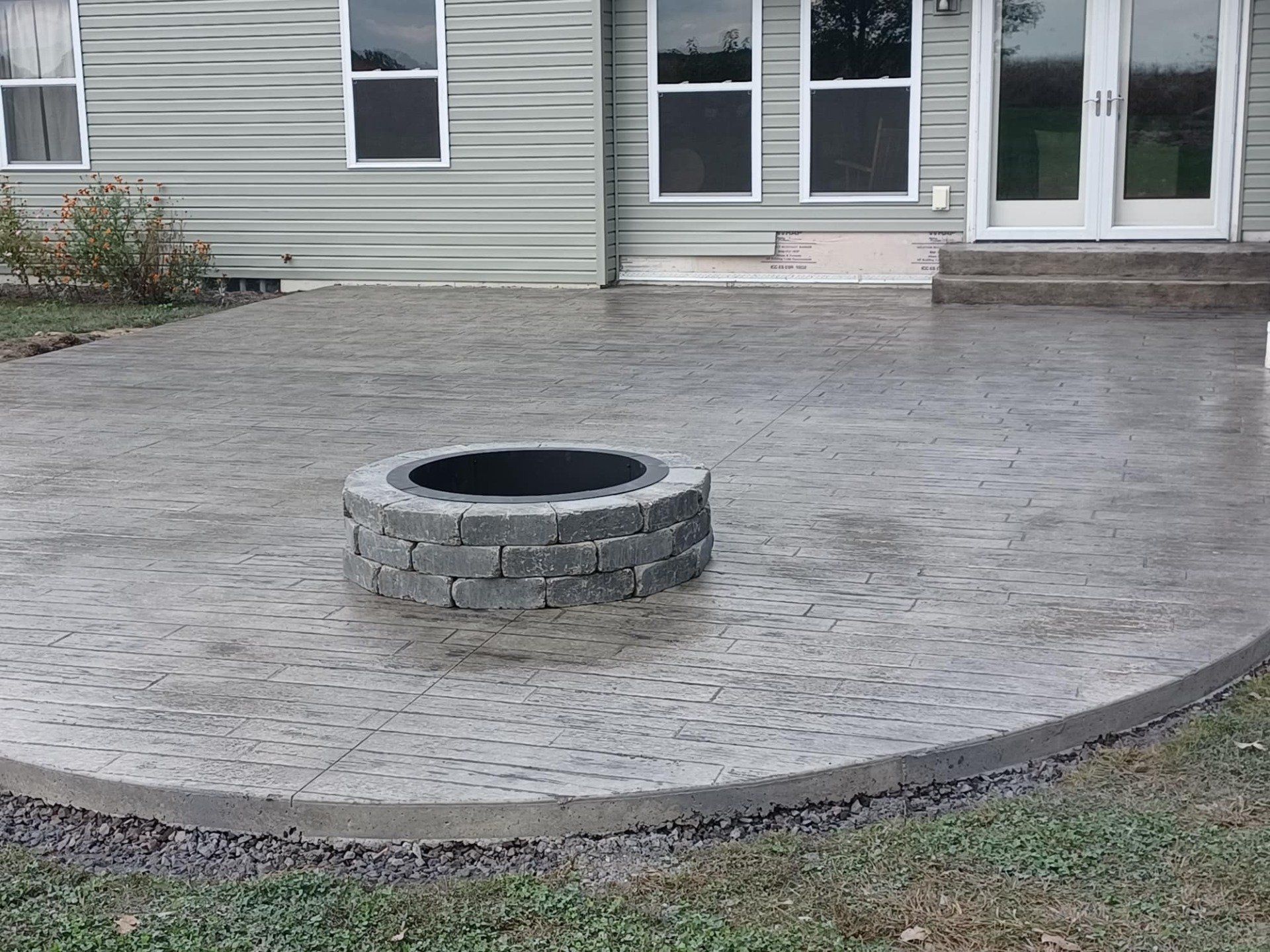 A fire pit on a patio in front of a house