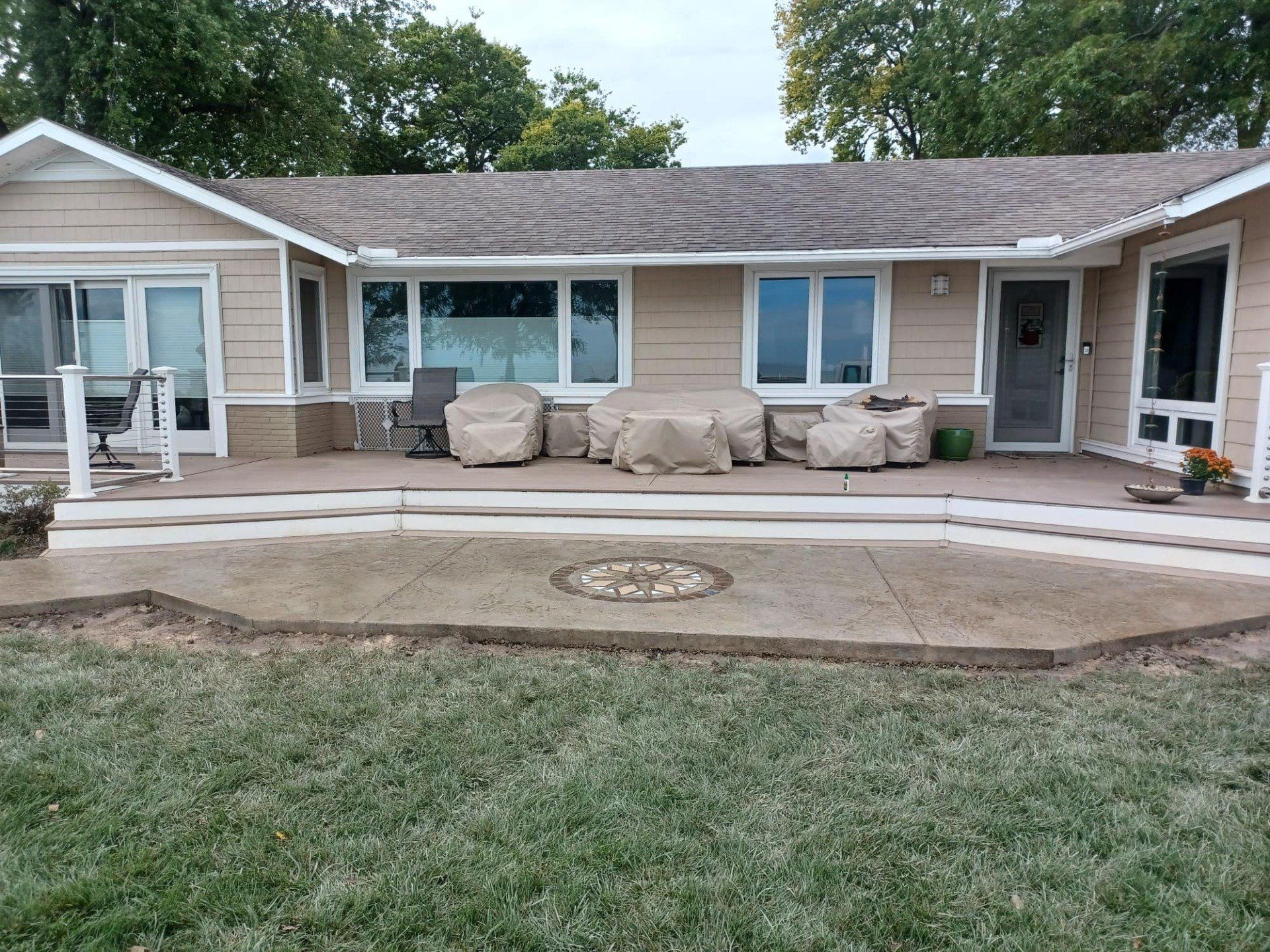 The back of a house with a patio and lawn in front of it.