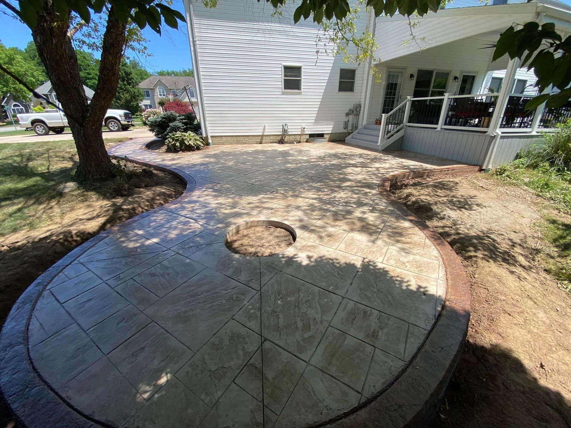 A patio with a fire pit in the middle of it in front of a house.