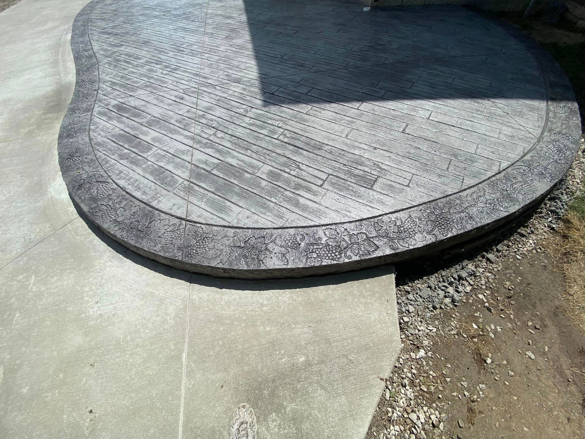 A concrete patio with a wooden table in the middle of it.